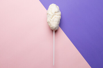 Horizontal image of homemade white candy floss on stick, on pink and purple with copy space