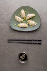 Foto op Plexiglas Overhead view of dumplings, soy sauce and chopsticks on grey background © vectorfusionart