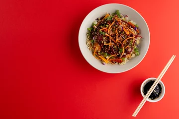 Foto op Plexiglas Overhead view of asian wok stir fry, soy sauce and chopsticks with copy space on red background © vectorfusionart
