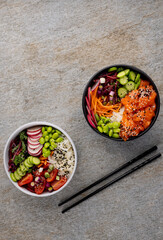 Overhead view of two hawaiian poke bowl with chopsticks with copy space on grey background