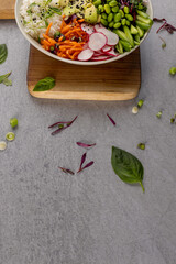 Overhead view of hawaiian poke bowl on wooden chopping board and grey background