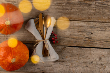 Overhead view of cutlery in napkin with autumn decoration and copy space on wooden background