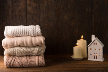 Obraz na płótnie Canvas Winter Knitted Sweaters and White Candles on Wooden Background.