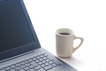 Obraz na płótnie Canvas コーヒーを飲みながらノートパソコン（黒）で仕事をする