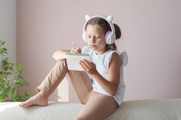A girl sits in headphones on the couch