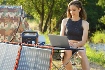 Woman uses solar panel and power station to generate electricity for laptop or smartphone