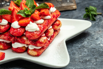 Tiramisu. Homemade tiramisu cake with fresh strawberry, mascarpone and mint. Tiramisu portion on plate on dark background. Delicious no bake tiramisu