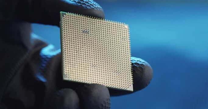 Close-up shot of gloved hand holding piece of Microchip.
