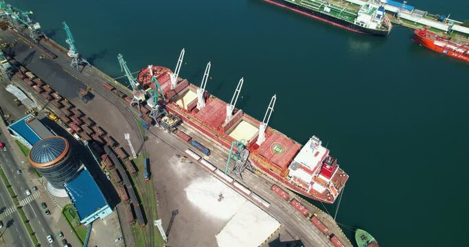 Cargo ship loading and unloading operations on board, aerial view. Cargo delivery by sea. The crane unloads the cargo ship. The concept of logistics by sea