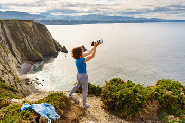 Tourist with camera on Asturias coast. Cabo Busto cliffs, Spain.