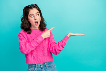 Portrait photo of young attractive pretty woman funny look directing finger hold hand empty space shock information isolated on cyan color background