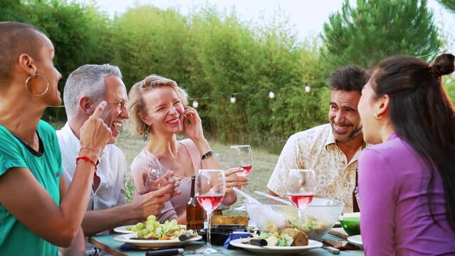 Group Of Adult Friends Or Familly Talking And Having Fun Sitting At Table In A Dinner Party In A Back Yard. High Quality 4k Slowmotion Footage