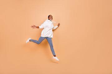 Fototapeta na wymiar Full length portrait of excited cheerful girl enjoy weekend free time isolated on beige color background
