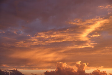 Bright colorful sunset sky with vivid smooth clouds illuminated with setting sun light spreading to horizon