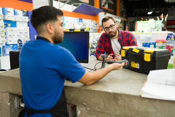 Young man paying for a tool box at the hardware store