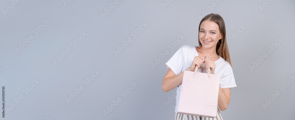 Wall mural teen girl doing shopping holding shopping bag in her hands fashion young woman shopper isolated on g