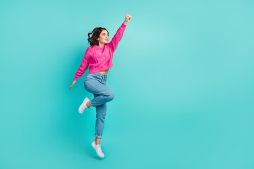 Full size photo of gorgeous powerful woman wavy hairstyle pink pullover jeans raise arm empty space isolated on teal color background