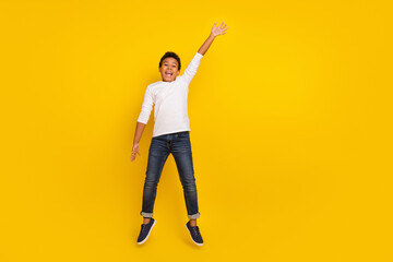 Photo of excited pretty schoolboy wear white shirt waving arms empty space isolated yellow color background