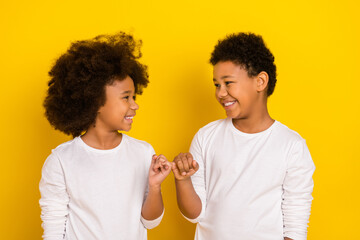 Photo of sweet friendly schoolboy schoolgirl wear white shirts holding small fingers isolated...