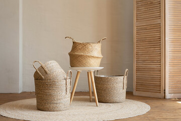 Various wicker baskets for interior decoration stand on the floor in a modern living room. - obrazy, fototapety, plakaty