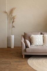 Sofa with macrame cushions on a wicker round rug in a modern living room in beige tones. Cozy...