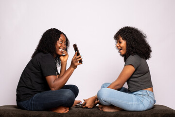african lady showing her friend something on her phone