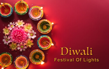 Happy Diwali - Clay Diya lamps lit during Diwali, Hindu festival of lights celebration. Colorful traditional oil lamp diya on red background