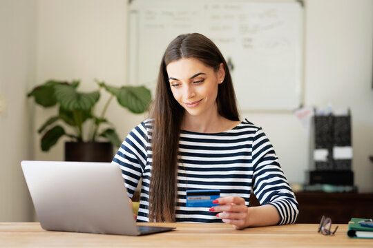 Attractive young woman using bank card and laptop while shopping online