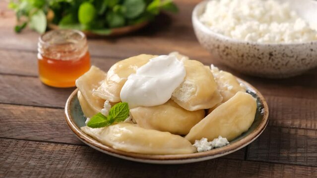 Ukrainian food Vareniki or steamed dumplings stuffed with sweet ricotta cheese or cottage cheese, served with thick yogurt or sour cream, closeup view