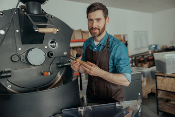 Business owner working with coffee roasting machine on own small factory