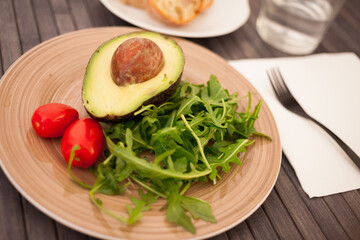 half an avocado, arugula and cherry tomatoes on plate
