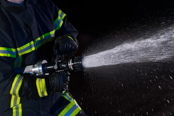 Firefighters use a water hose to eliminate a fire hazard. Team of firemen in the dangerous rescue...