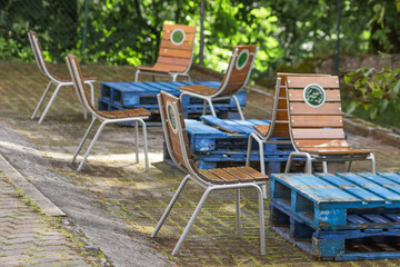 Summer cafe area with blue wooden tables and vintage chairs in the old marine style in quiet place of backyard.