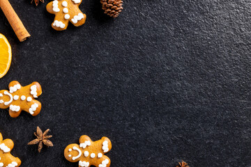 Image of gingerbread man cinnamon sticks and christmas decoration with copy space on black