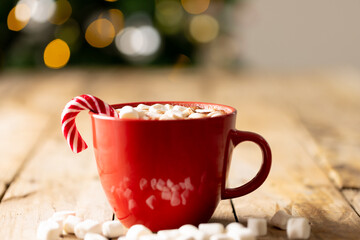Image of red cup with hot chocolate and marshmallows and copy space over christmas tree
