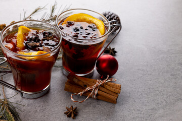 Image of two cups of tea with spices and lemon and christmas decorations with copy space on grey