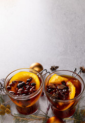 Image of two cups of tea with spices and lemon and christmas decorations with copy space on grey