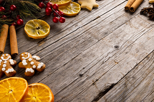 Image of gingerbread man cinnamon sticks and christmas decoration with copy space on wood