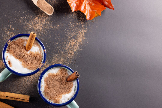 Image of two christmas mugs of milk with cinnamon with copy space on grey