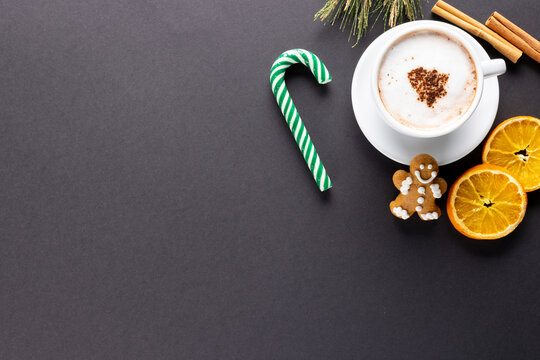Image of cup of cappuccino coffee and christmas gingerbread man with copy space on grey