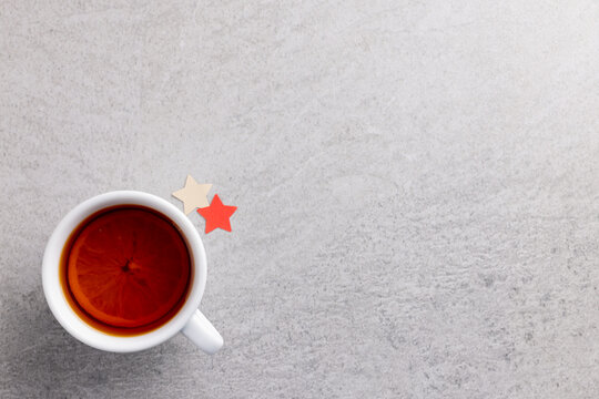 Image of glass of lemon tea with stars christmas decoration and copy space on grey background