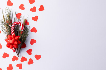 Christmas cane, gifts, christmas tree twigs and red hearts over white background