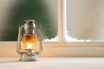 Vintage christmas shining oil lantern over frozen and snowy window