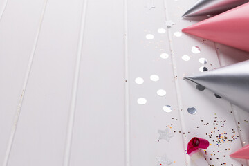 Image of confetti and party hats lying on white wooden surface