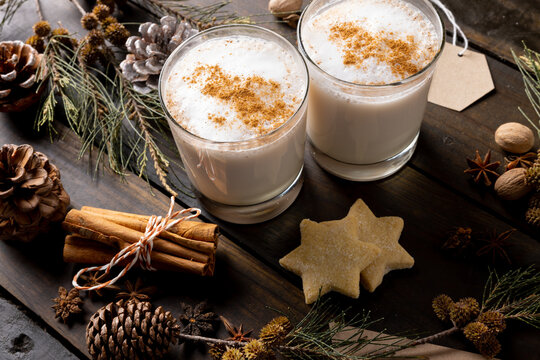 Image of two glasses of christmas milk with cinnamon sticks and christmas decorations