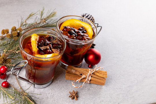 Image of two cups of tea with spices and lemon and christmas decorations with copy space on grey