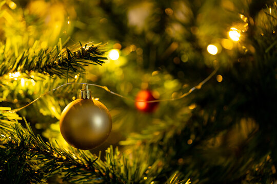 Glowing christmas lights and christmas balls over green christmas tree