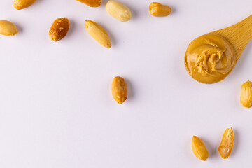 Image of spoon with peanut butter and nuts on white surface