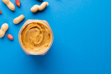 Image of peanut butter jar and nuts on blue background