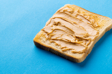 Image of bread slice with peanut butter on blue background